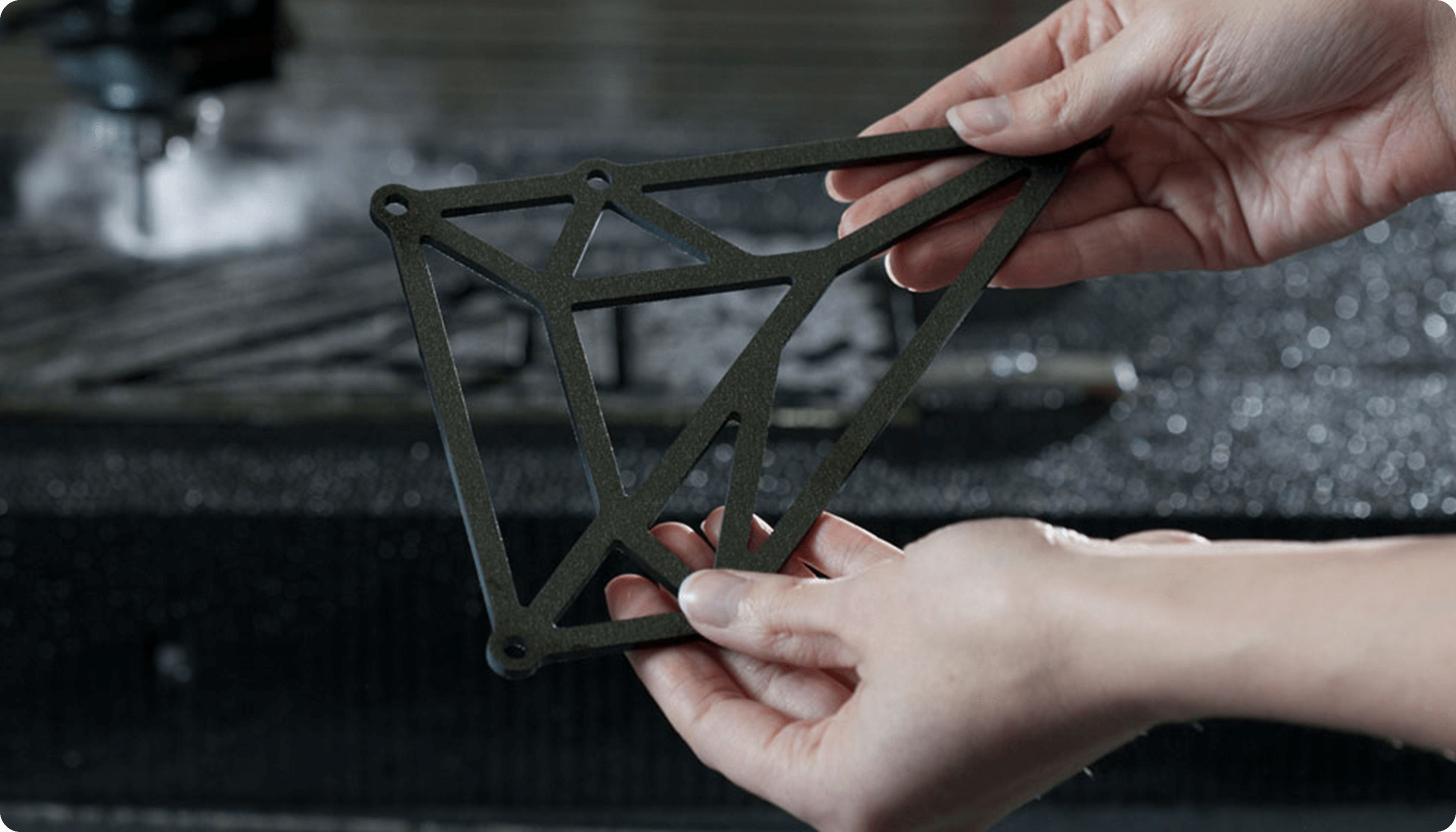 Two hands holding an intricate composite part cut by waterjet