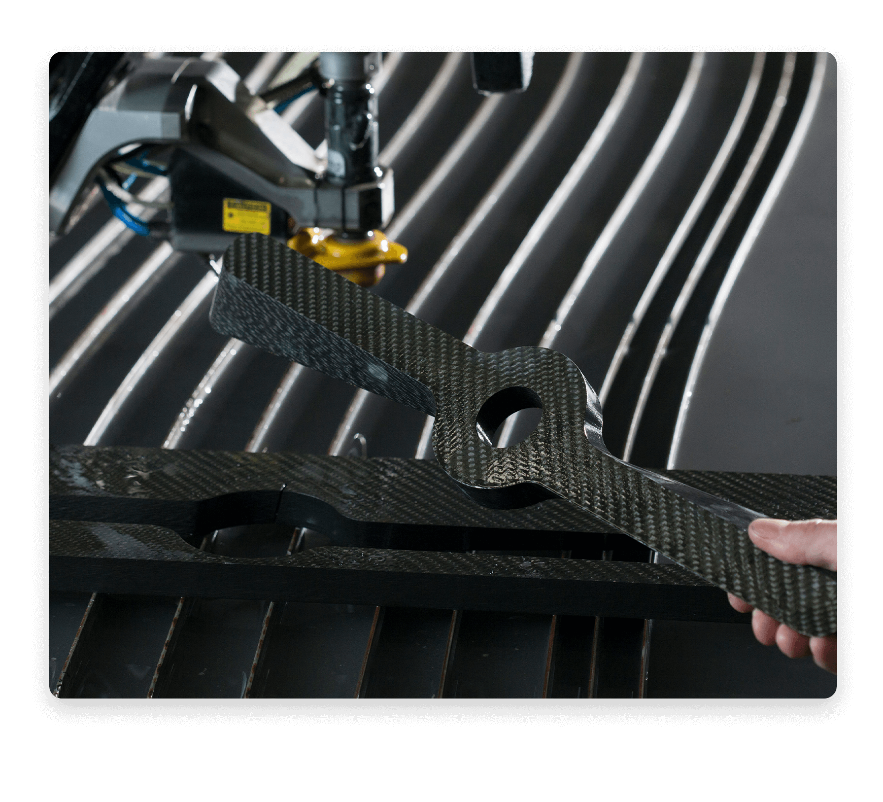 Person holding a composite waterjet cut part over the cutting table.